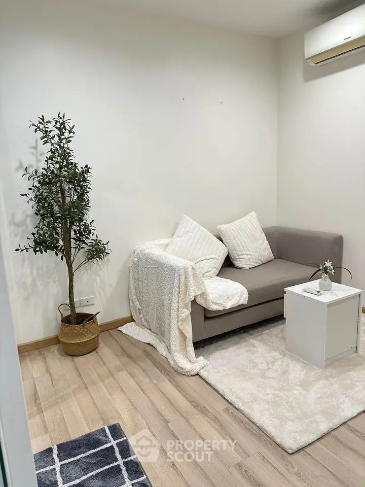 Cozy living room with modern sofa, stylish decor, and air conditioning unit