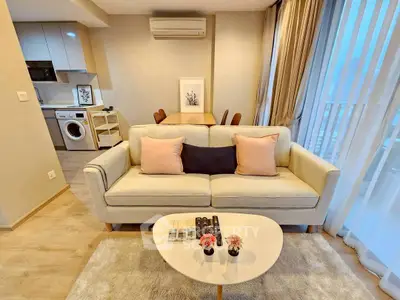 Modern living room with cozy sofa, dining area, and washing machine in open layout.