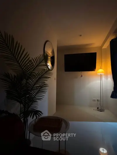 Cozy living room with modern decor, featuring a wall-mounted TV and ambient lighting.