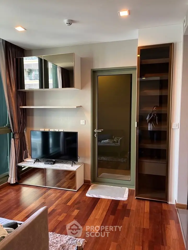 Modern living room with sleek TV setup and wooden flooring in a stylish apartment.