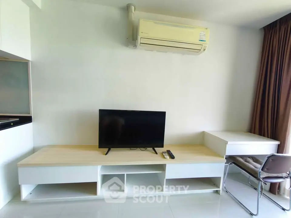 Modern living room with sleek TV setup and air conditioning in a stylish apartment.