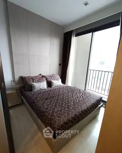 Modern bedroom with large window and stylish bedding in a contemporary apartment.
