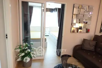 Modern living room with glass door leading to a bright bedroom, featuring stylish decor and cozy ambiance.