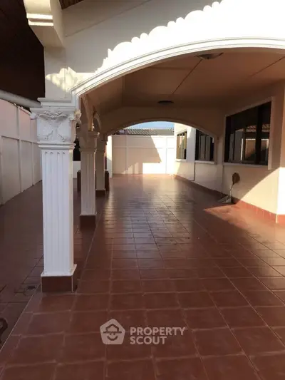 Spacious covered terrace with elegant columns and tiled flooring, perfect for outdoor gatherings.