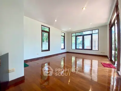 Spacious living room with polished wooden floors and large windows offering natural light.