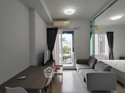 Modern studio apartment with balcony and city view, featuring a cozy living area and sleek furnishings.