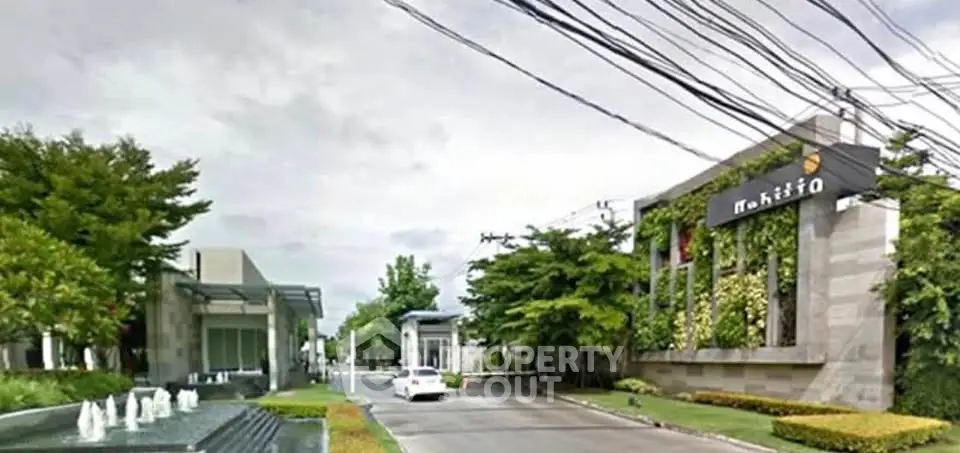 Luxurious gated community entrance with lush greenery and modern architecture.