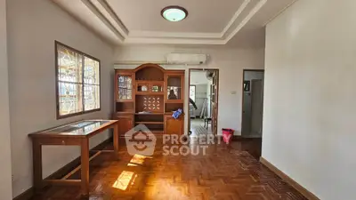 Spacious living room with wooden flooring and elegant furniture, perfect for family gatherings.