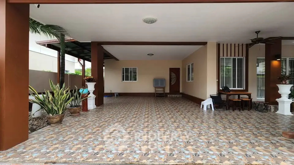 Spacious covered patio with tiled flooring and potted plants in a modern home.