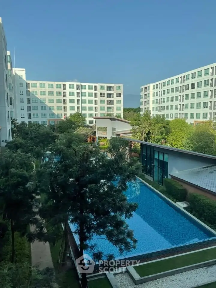 Stunning apartment complex with a large pool and lush greenery, offering a serene living environment.
