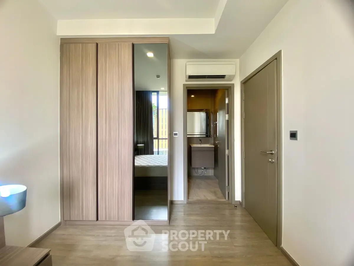 Modern bedroom with mirrored wardrobe and en-suite bathroom in stylish apartment.