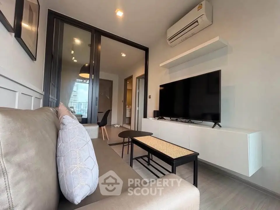 Modern living room with sleek design, featuring a comfortable sofa, large TV, and air conditioning.