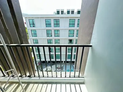 Modern apartment building view from balcony with sleek design and pool area.