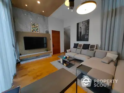 Spacious living room with modern furnishings, large sectional sofa, and a sleek entertainment wall unit, complemented by elegant hardwood floors and contemporary lighting.