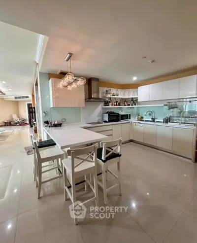 Spacious modern kitchen with sleek white cabinets and stylish lighting in open layout design.