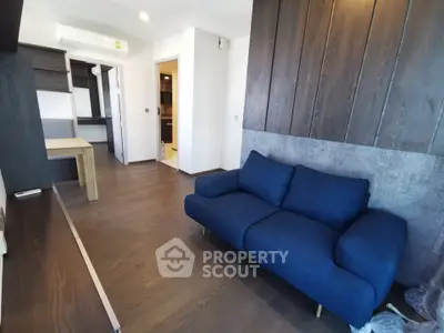 Modern living room with dark wood paneling and blue sofa, featuring sleek design and open layout.