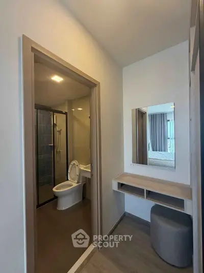 Modern bathroom with sleek design and adjacent vanity area in a contemporary apartment.
