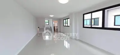 Spacious and bright living room with large windows and glossy tiled floors in modern home.