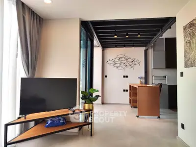 Modern living room with stylish decor and open kitchen layout, featuring sleek furniture and natural light.