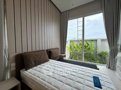 Modern bedroom with large window and garden view, featuring sleek design and natural light.