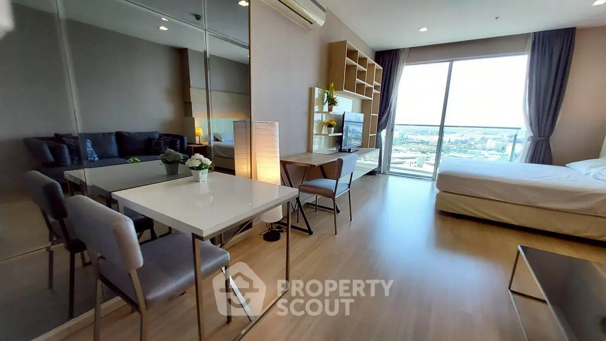Modern studio apartment with open layout, featuring a cozy living area, dining space, and large window with city view.