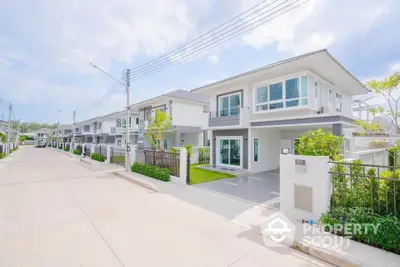 Modern two-story house with clean lines and lush greenery in a serene neighborhood.