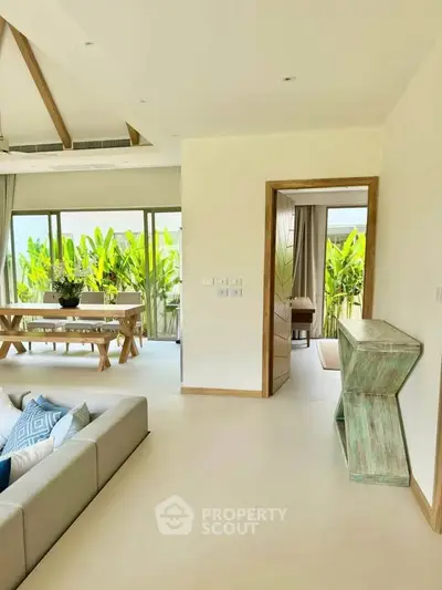 Spacious living room with modern decor and large windows opening to a lush balcony view.