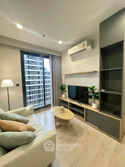 Modern living room with balcony view, stylish furniture, and air conditioning in a high-rise apartment.