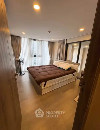 Cozy bedroom with large windows and modern decor, perfect for relaxation.