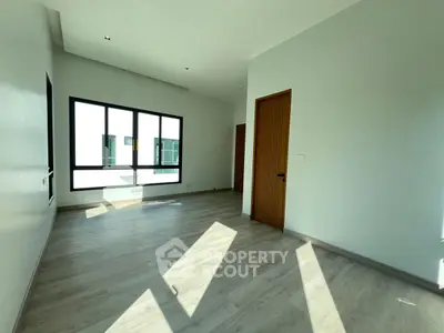 Spacious sunlit room with modern flooring and large windows in a contemporary home.