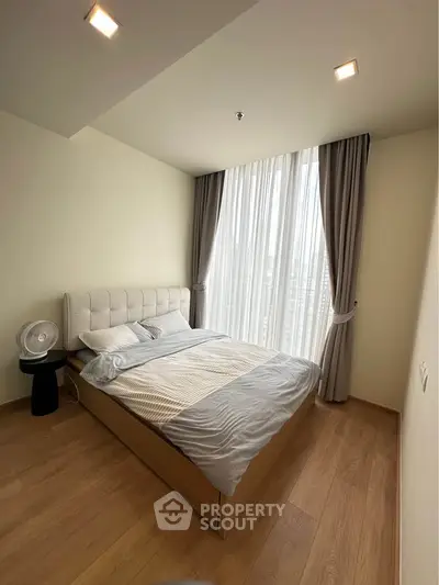 Modern bedroom with large window and elegant curtains in a stylish apartment.