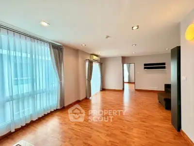 Spacious modern living room with wooden flooring and large windows in a stylish apartment.