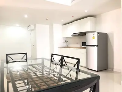 Modern kitchen with dining area featuring sleek appliances and stylish glass table.