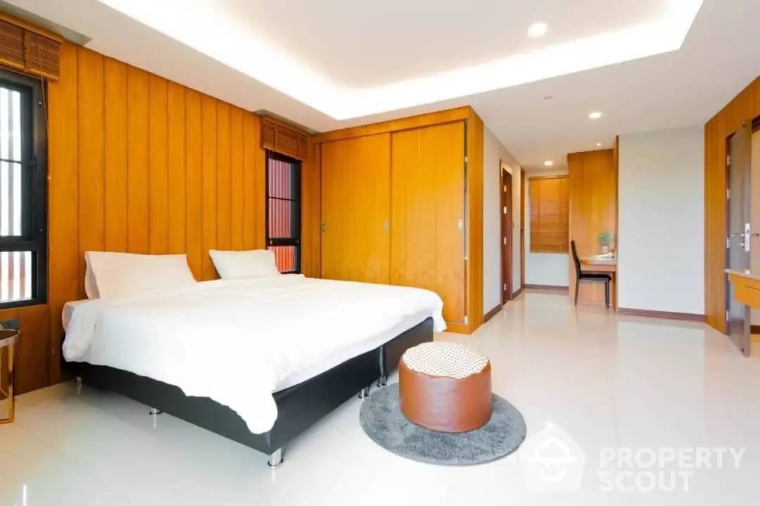 Spacious bedroom with polished floors, large bed, and warm wooden accents offering a serene and inviting atmosphere.