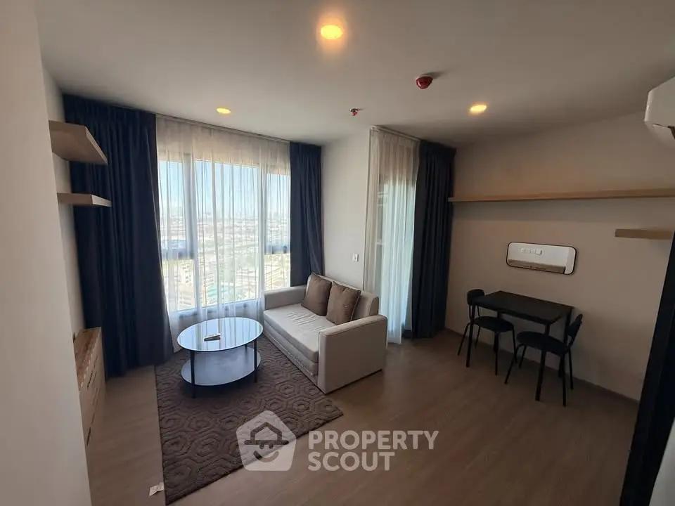 Modern living room with large windows and stylish furniture in a high-rise apartment.