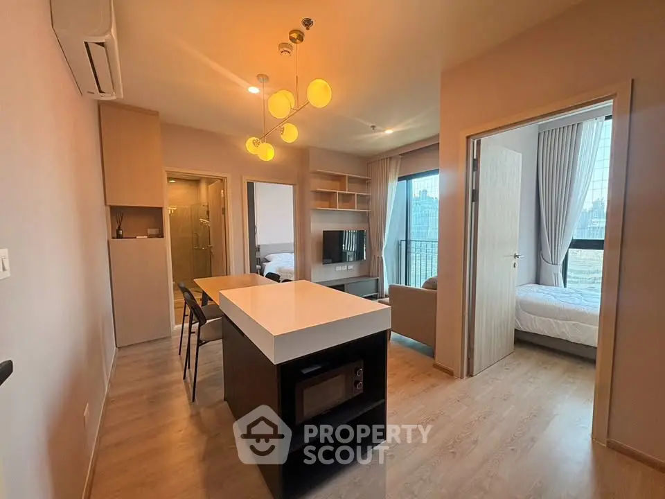 Modern apartment interior with open kitchen and cozy living area, featuring stylish lighting and city view.