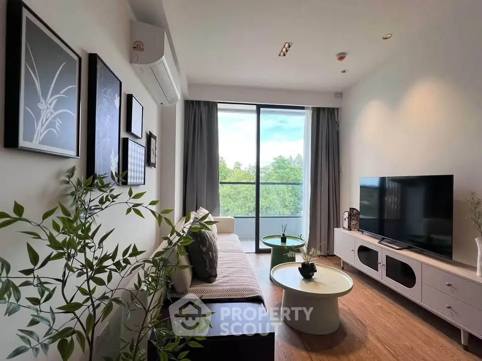 Modern living room with stylish decor and large window offering lush green view.