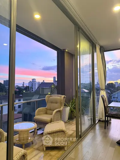 Stunning balcony view with cozy seating and vibrant sunset over city skyline.
