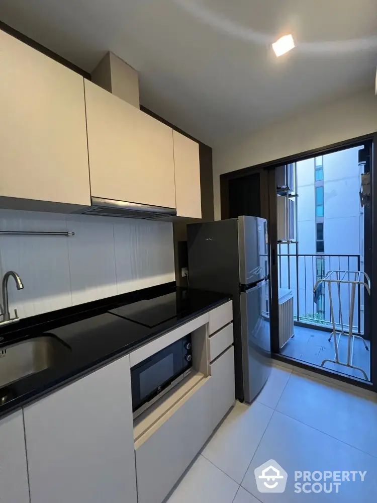 Modern kitchen with sleek cabinets and balcony access in urban apartment