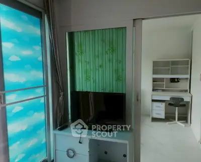 Modern apartment interior with sliding doors, TV unit, and study area with desk and chair.