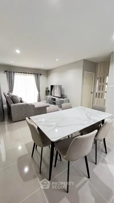 Modern open-plan living and dining area with elegant marble table and cozy seating.