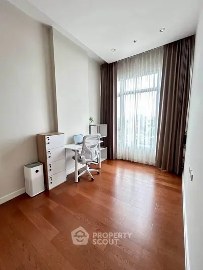 Bright study room with modern desk and chair, hardwood floors, and large window with sheer curtains.