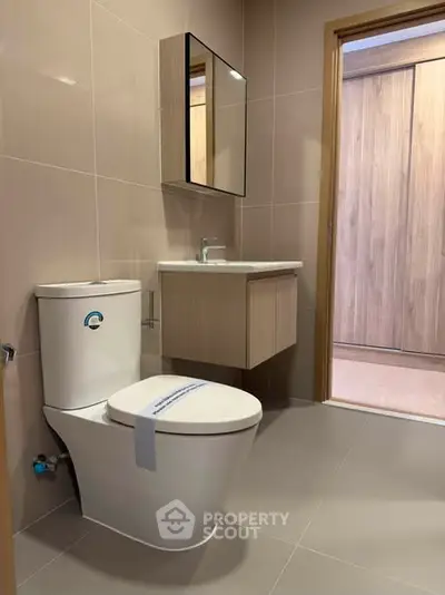 Modern bathroom with sleek fixtures and neutral tones, featuring a stylish vanity and contemporary toilet design.