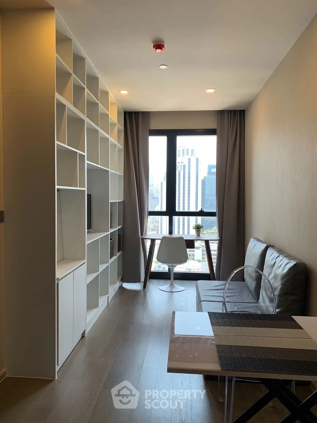 Modern living room with city view, sleek furniture, and built-in shelving in urban apartment.