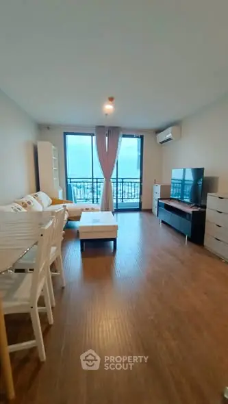 Spacious living room with modern furniture and balcony view in a high-rise apartment.
