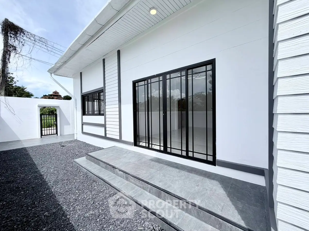 Modern white exterior with sleek black window frames and gravel pathway