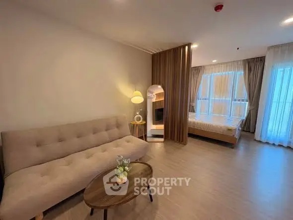 Modern open-layout living room with cozy sofa and bedroom view, perfect for urban living.