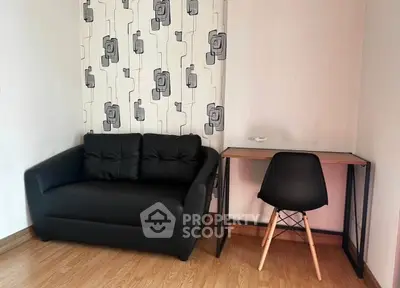 Modern living room with stylish black sofa and minimalist desk setup.