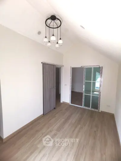 Spacious room with elegant sliding doors and modern light fixture, featuring sleek wooden flooring.