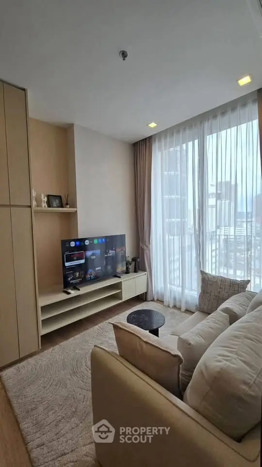 Modern living room with city view, cozy sofa, and entertainment setup in a high-rise apartment.